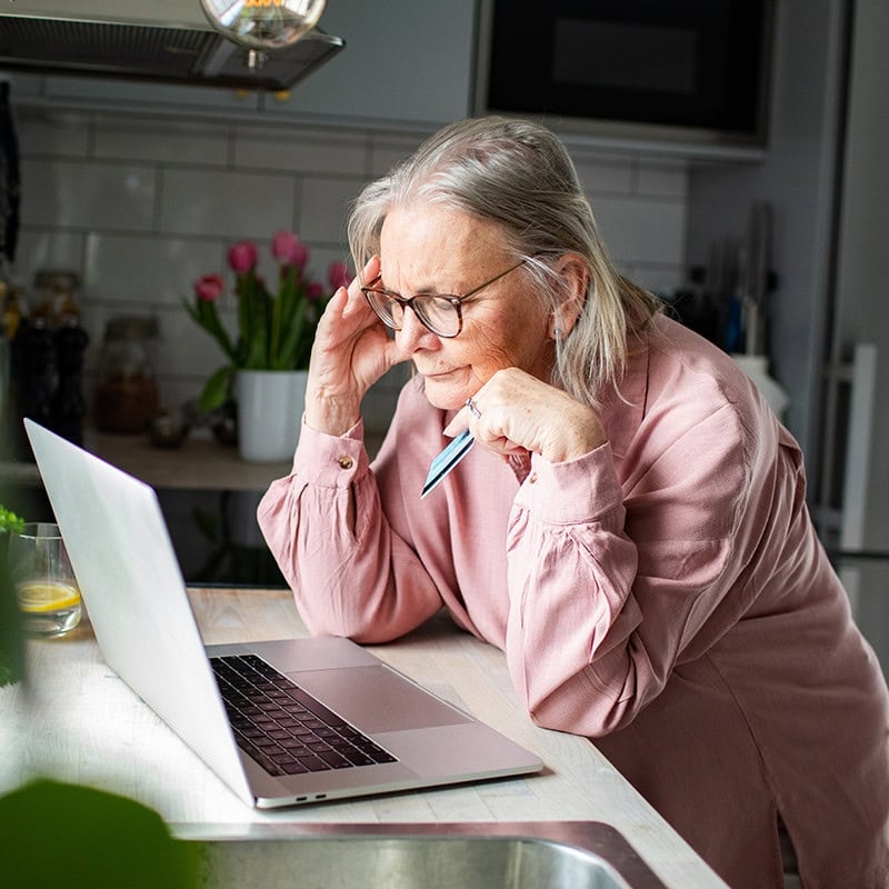 older woman concerned with laptop and credit card
