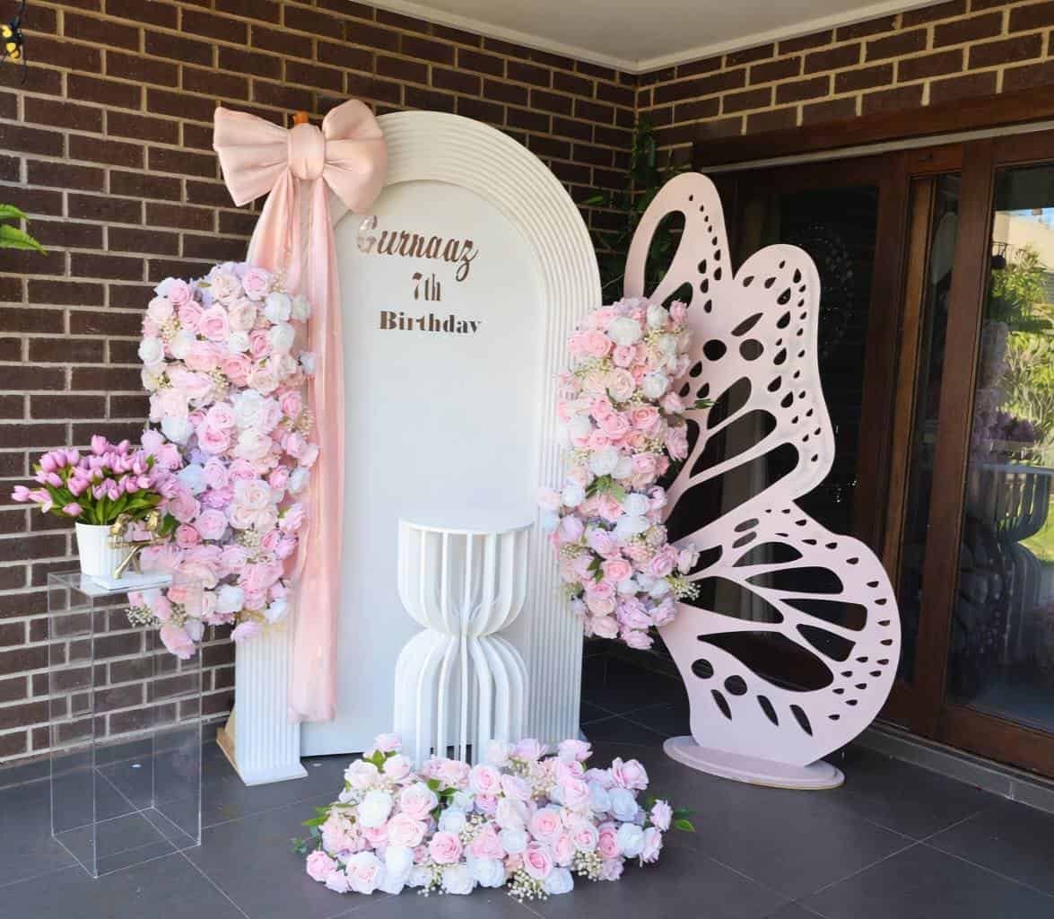 Elegant floral birthday backdrop with pink roses and butterfly decor.