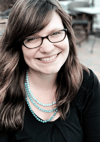 Jodi Snowdon smiling, wearing glasses and turquoise necklaces.