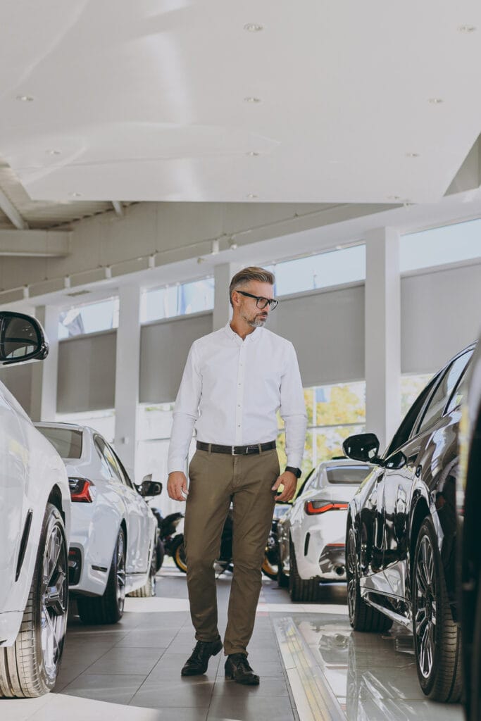 High-end man inspecting luxury cars in a modern showroom for automotive advertising.