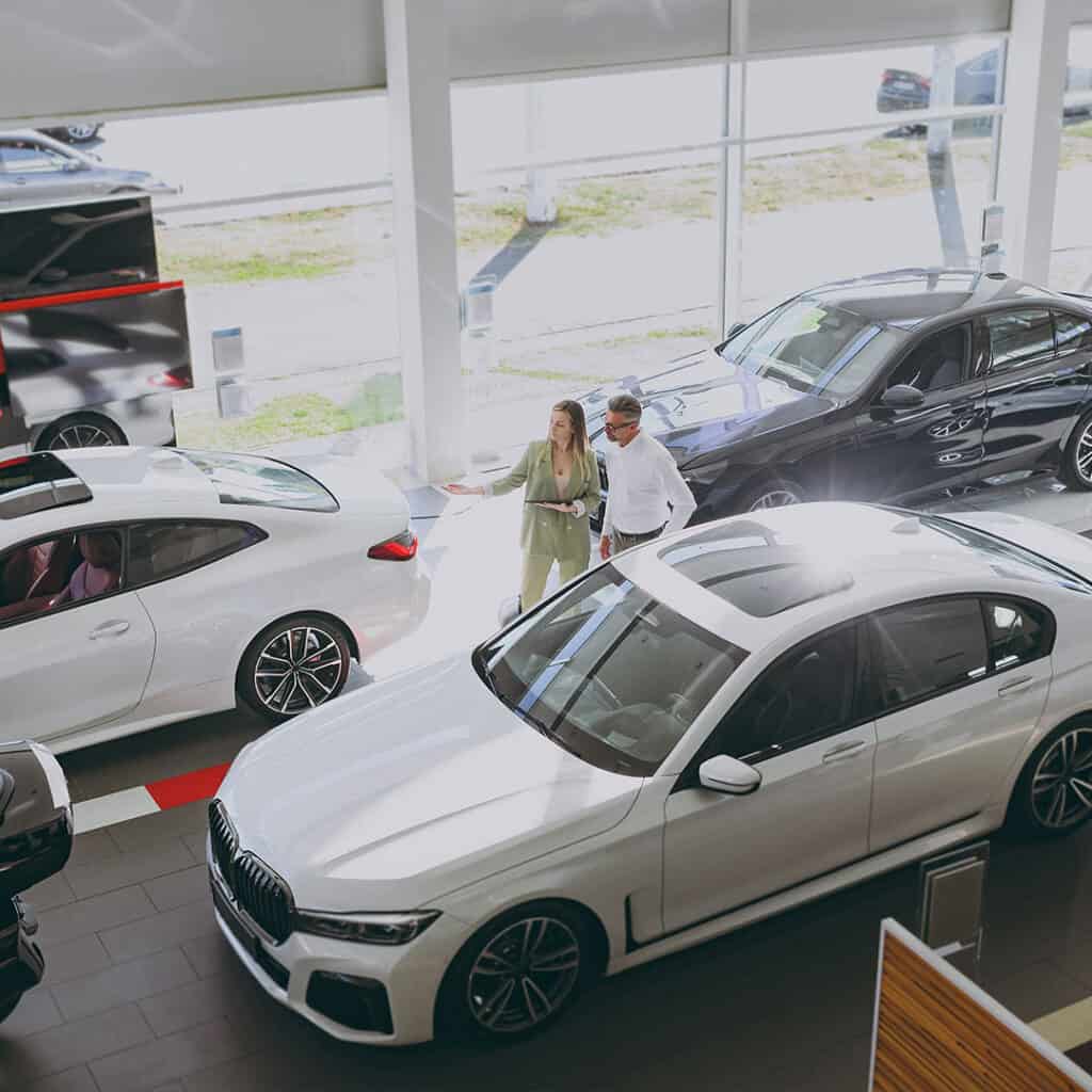 Luxury car dealership showcasing premium vehicles inside a modern showroom with sales representatives.