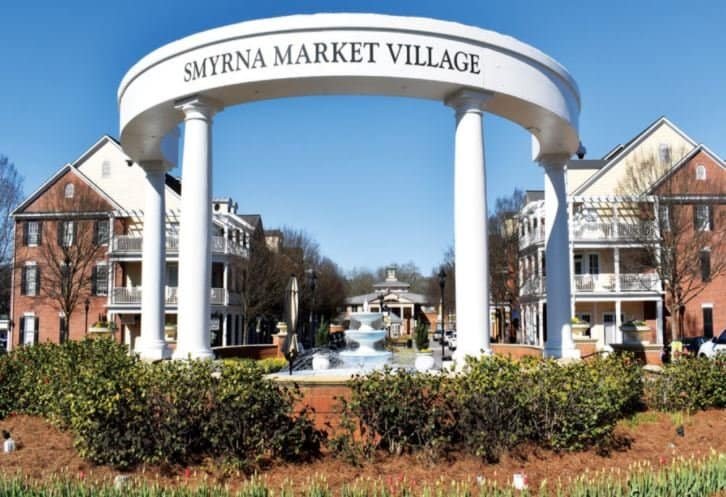 Smyrna Market Village entrance with welcoming arch and fountain, showcasing a vibrant shopping and c.