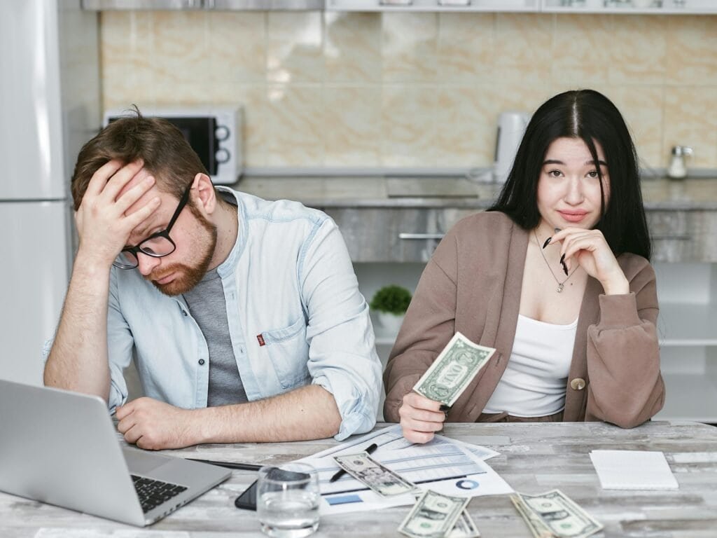 Frustrated couple reviewing finances during tax season at home.