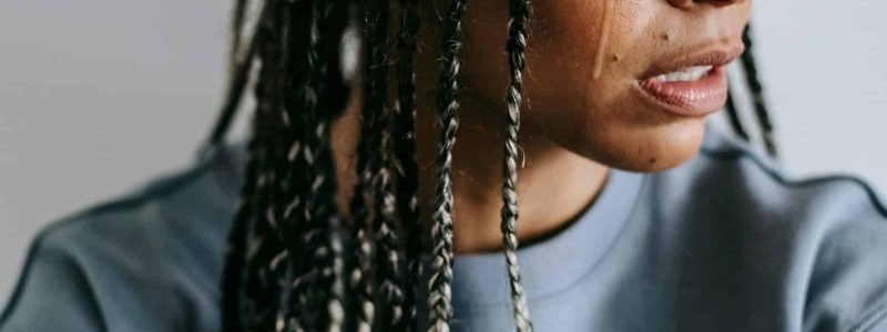Female with braided hair looking sideways, casual indoor setting.