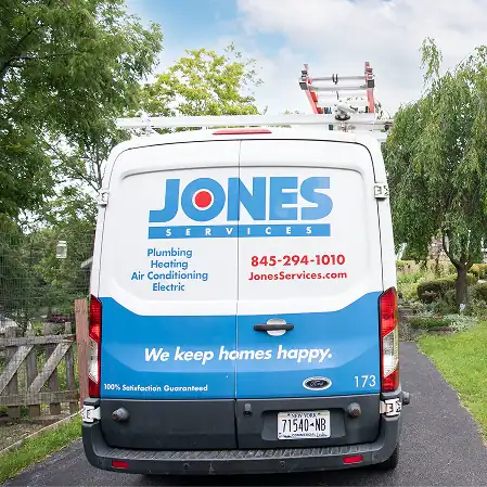 A white Jones Services van, parked on a driveway, displays company branding and contact information for plumbing, heating, air conditioning, and electric services within the local service area.