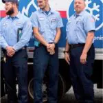 Three men in blue uniforms stand in front of a truck with a logo featuring flames and a snowflake.