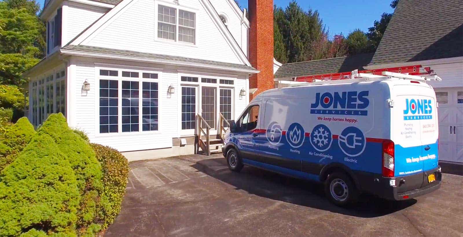 A service van with "Jones Services" logo is parked in the driveway of a white house with large windows and a prominent chimney.