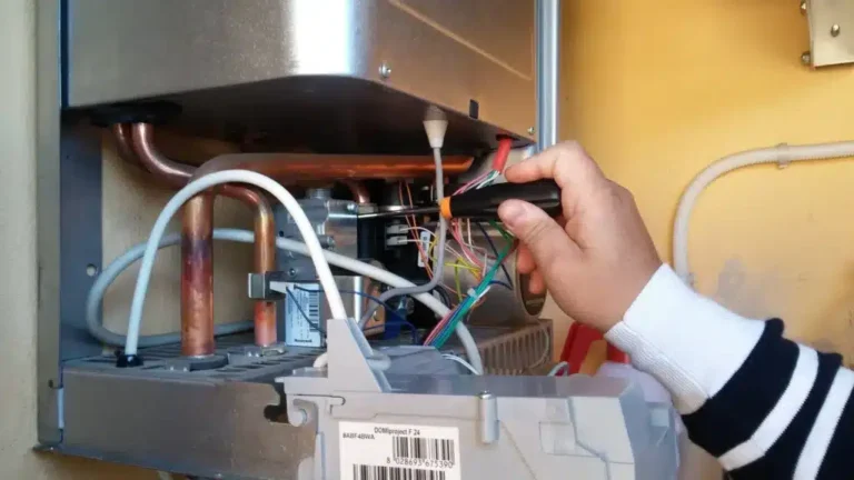 A person uses a screwdriver to adjust wiring in a mechanical unit, meticulously preparing for an oil to gas conversion, with visible pipes and cables intertwined in the complex setup.