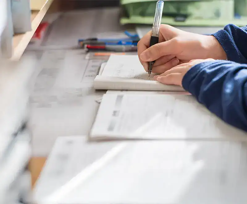 Person writing in notebook at desk