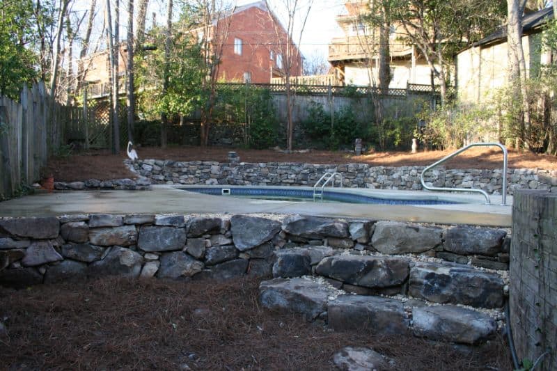 Concrete pool with stone retaining wall and landscaping, designed by John Russell Landscape Architect, showcasing premium outdoor living and backyard transformation.