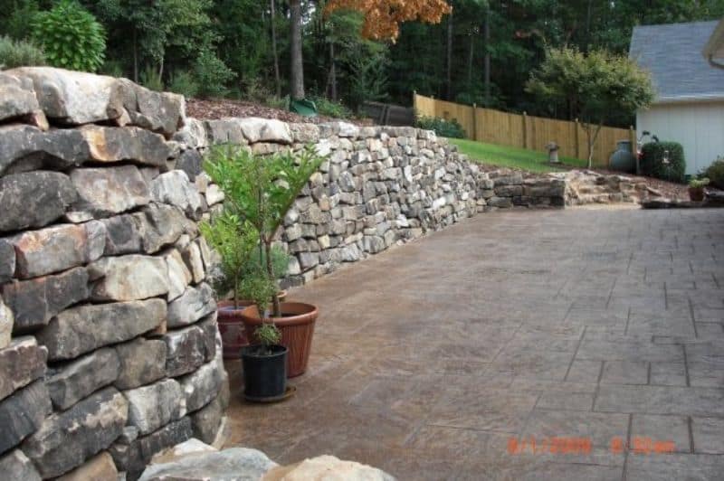 2. Beautiful stone retaining wall and paver patio design by John Russell Landscape Architect in a landscaped backyard.