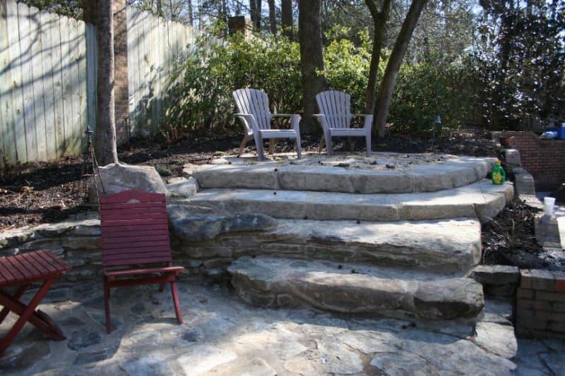 Natural stone layered patio with outdoor seating and landscaping; landscape architecture by John Russell Landscape Architect.