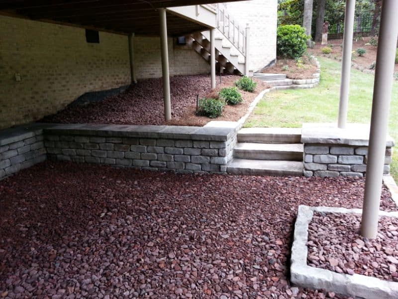 Decorative stone retaining wall and landscaping design by John Russell Landscape Architect for residential outdoor space.
