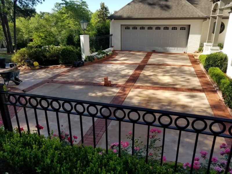 Concrete driveway with brick accents designed by John Russell Landscape Architect, featuring lush landscaping and a clean, modern aesthetic.