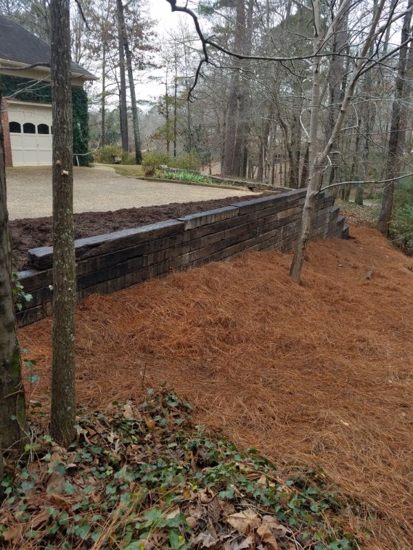 Natural landscape design with a decorative stone retaining wall and lush woodland setting for a residential yard.