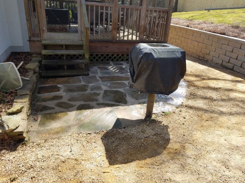 Natural stone patio installation with a covered grill on a backyard deck, showcasing landscape design, outdoor living space, and hardscape features by John Russell Landscape Architect.