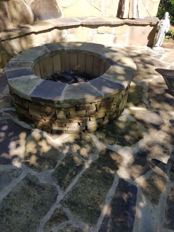 Fire pit made of stacked natural stone for outdoor landscape design, perfect for backyard entertainment and relaxation, designed by John Russell Landscape Architect.