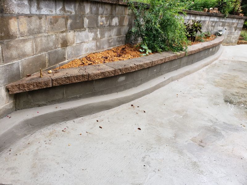 Curved concrete and brick planter bed with landscaping, designed by John Russell Landscape Architect, featuring layered planting beds and durable materials for elegant garden borders.