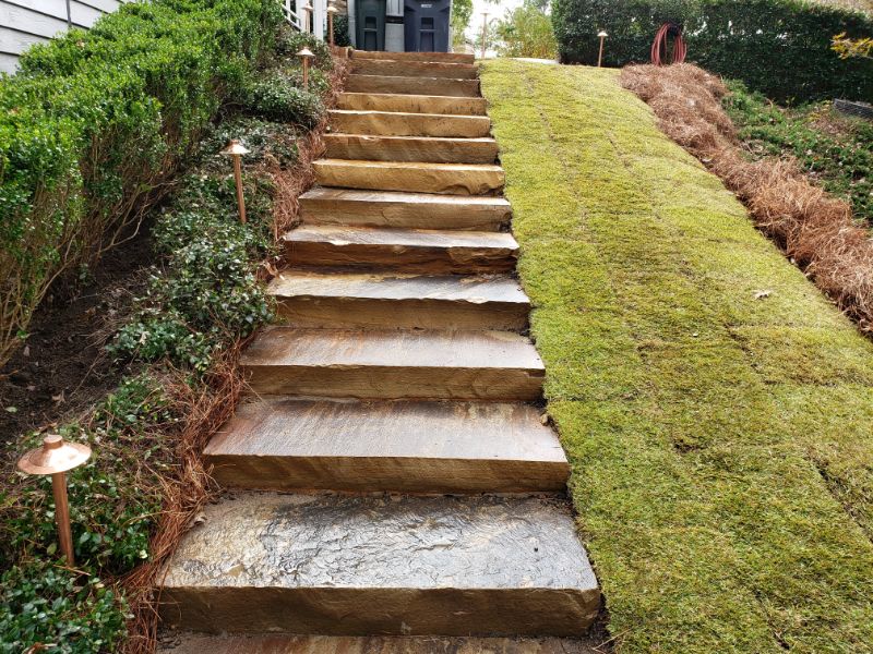 Natural wood landscape stairs with mossy lawn and garden lighting for hillside garden design.