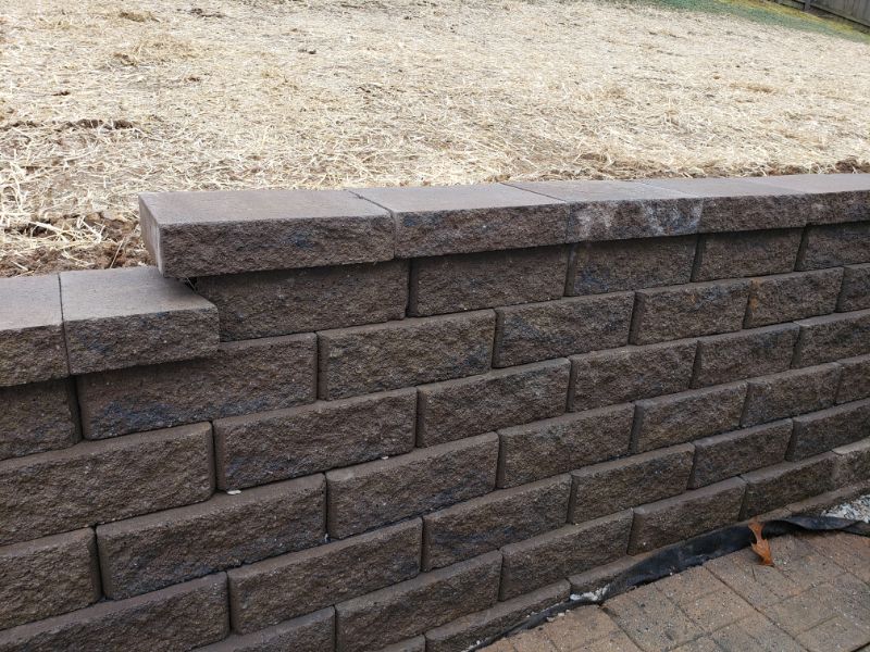 Layered brick retaining wall installation by John Russell Landscape Architect showcasing durable landscape design.