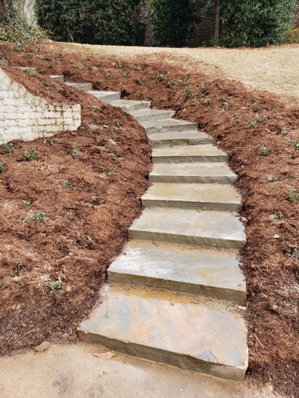 Natural stone garden stairway with concrete steps in a landscaped yard of a residential property.