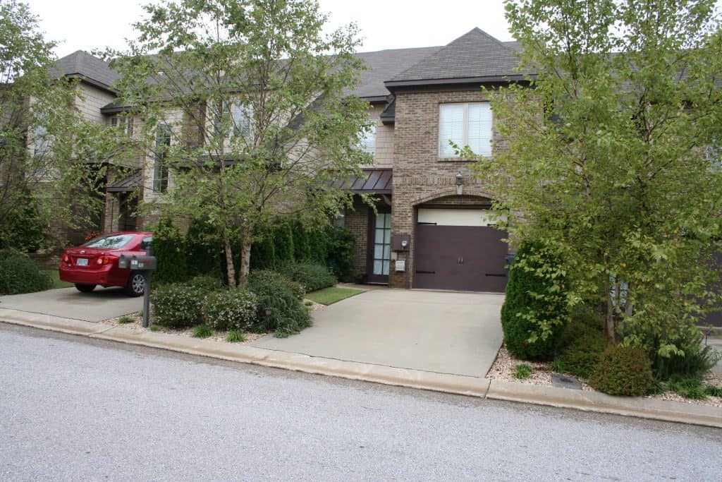 Modern brick house with landscaped front yard and driveway, showcasing professional landscape architecture by John Russell Landscape Architect in a suburban neighborhood.
