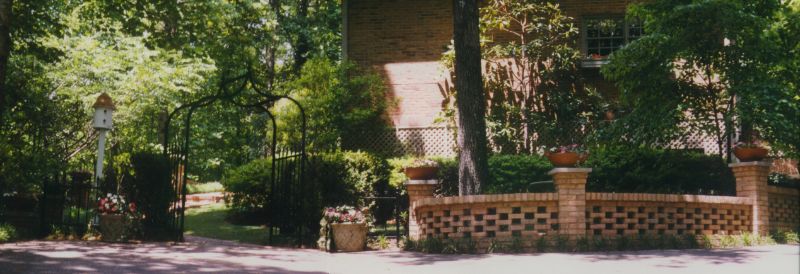 Lush landscaped garden with brick and stone features, pathway, and vibrant greenery in a professional landscape design by John Russell Landscape Architect.