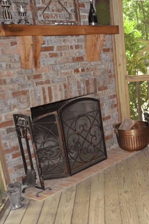 Fireplace with brick surround and wrought iron screen in a cozy interior setting.