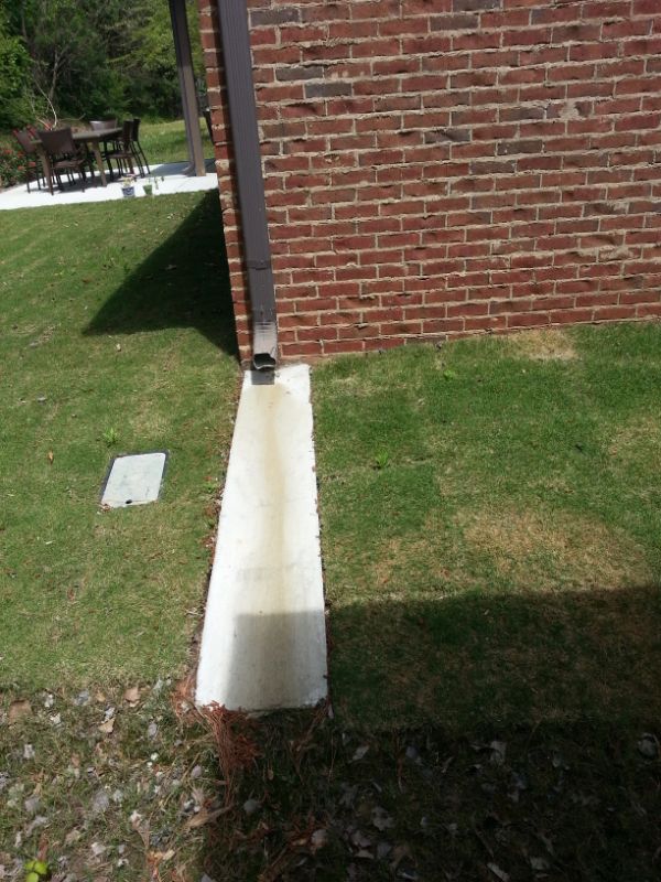 Concrete sidewalk leading to the back of a brick house with landscaping, designed by John Russell Landscape Architect.