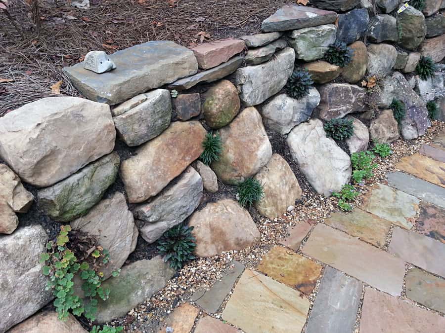 Natural stone garden retaining wall with landscaping and low-maintenance plants, designed by John Russell Landscape Architect.