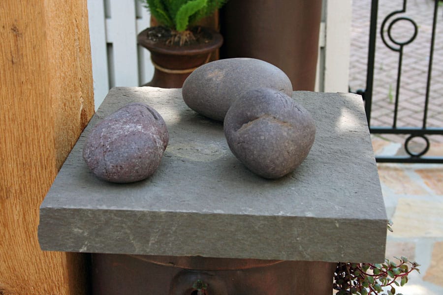 Natural stone garden decoration with four smooth river rocks on a textured stone slab. Perfect for landscape design and outdoor aesthetic enhancement.