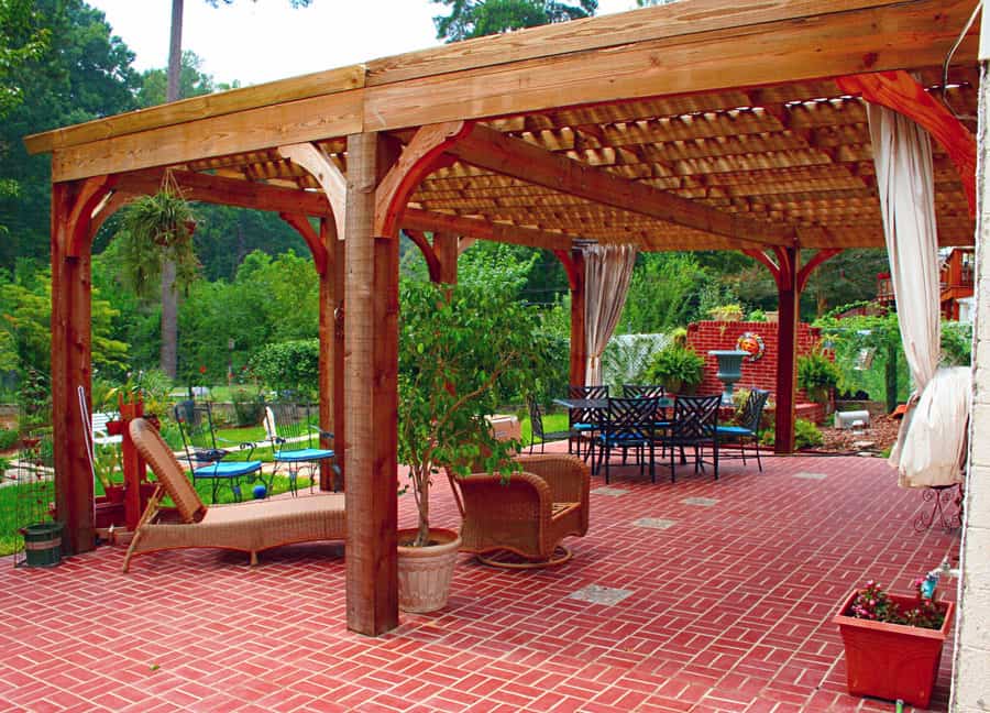 Pergola outdoor patio designed by John Russell Landscape Architect with brick flooring, cozy seating, lush greenery, and landscape planting, creating an inviting garden space for relaxation and entertaining.