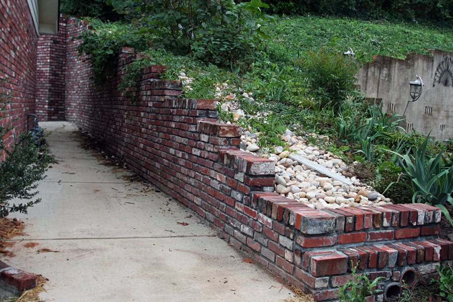 Brick retaining wall with landscaping design by John Russell Landscape Architect, showcasing outdoor garden aesthetics and durable brickwork.