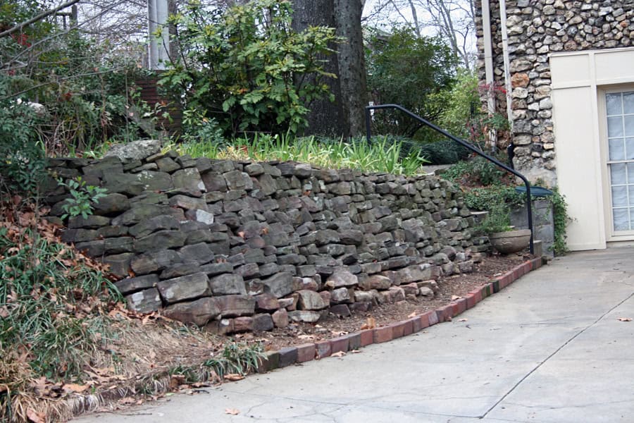 Rammed stone retaining wall with planting bed and garden steps showcasing professional landscape architecture by John Russell Landscape Architect.