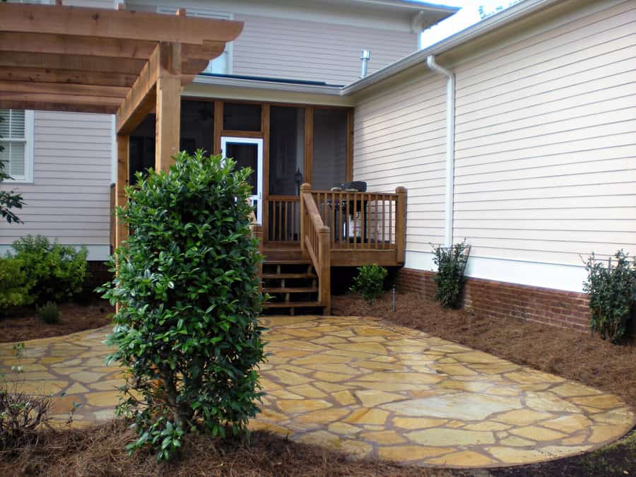 Enhanced backyard landscape design with a custom wooden deck and flagstone patio by John Russell Landscape Architect. Skilled outdoor space planning for aesthetic and functional outdoor living.