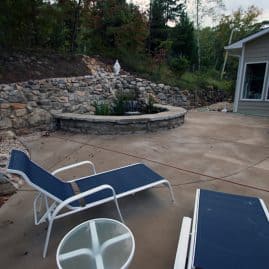 Fire pit landscape design with stone retaining wall, outdoor patio, and seating area at john russell landscape architect.