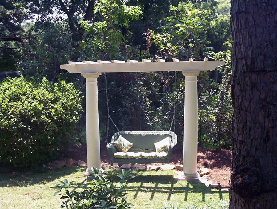 Aesthetic garden swing under pergola with lush greenery in the background, designed by John Russell Landscape Architect, showcasing elegant outdoor landscape architecture.