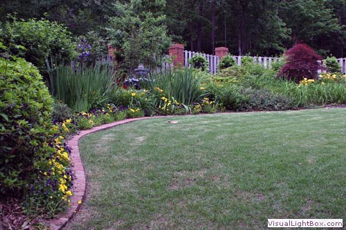 Lush garden landscape with vibrant flowers, trimmed lawn, and decorative borders created by John Russell Landscape Architect.