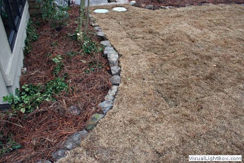 Natural stone garden border separating mulch bed from lawn in a landscape design by John Russell Landscape Architect.