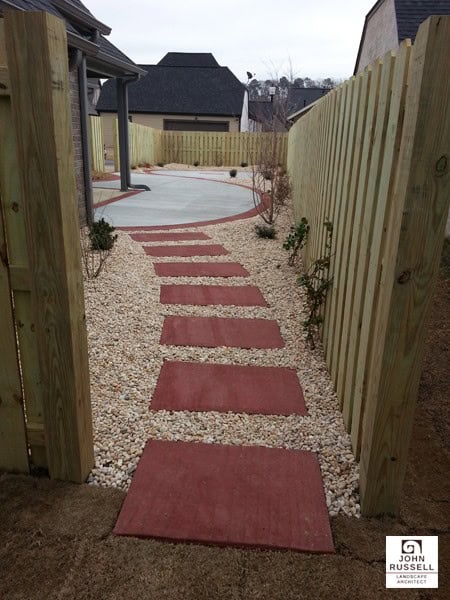 Red stepping stones pathway leading to backyard with gravel border, wooden fence, and modern house in the background, designed by John Russell Landscape Architect.