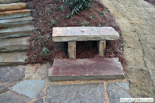 Weathered wooden garden bench with stone pathway, landscape design by John Russell Landscape Architect.