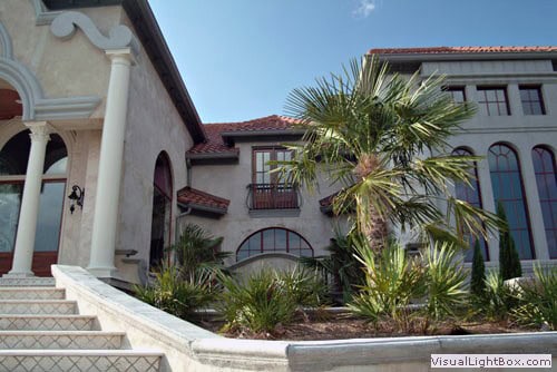 Luxurious Mediterranean-style landscape design featuring lush palm trees and elegant architecture by John Russell Landscape Architect.