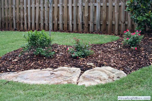 Manicured garden landscape with flower beds, mulch, stone edging, and lush lawn by John Russell Landscape Architect, specializing in custom residential landscape design and garden architecture.