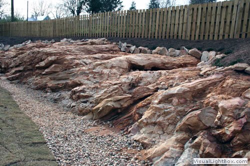 Natural rock landscape design with boulders and gravel for hillside erosion control and aesthetic enhancement.