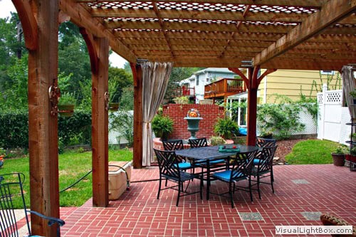 Elegant backyard pergola with brick patio, outdoor dining table, and lush garden landscaping by John Russell Landscape Architect. Perfect for outdoor entertaining and garden design.