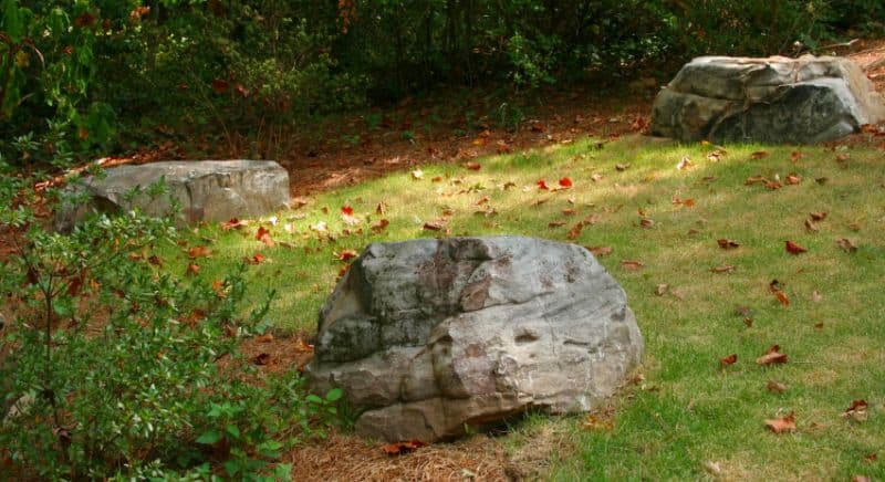 Crushed granite boulders in a landscaped garden setting with lush greenery, designed by John Russell Landscape Architect for elegant outdoor spaces.