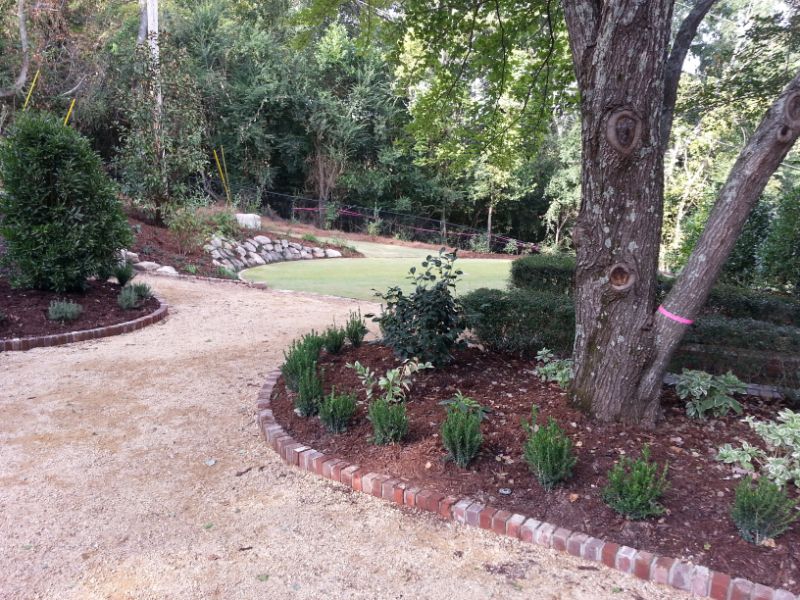 Lush landscaped garden with mature trees, shrubbery, and a gravel pathway, designed by John Russell Landscape Architect, showcasing professional outdoor space design and sustainable landscape solutions.