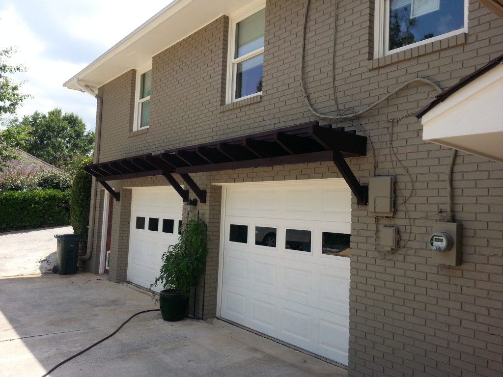 Modern residential garage with custom black pergola and lush potted plant, designed by John Russell Landscape Architect. Perfect blend of functionality and aesthetic appeal in landscape design.