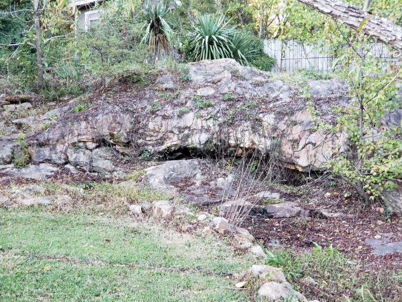 Natural rock garden with boulder formations and lush shrubbery, expertly designed by John Russell Landscape Architect for harmonious outdoor aesthetic.