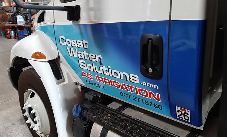 Partial vehicle wrap on the cab of an International flatbed truck for Coast Water Solutions, designed and installed by J. Thow.